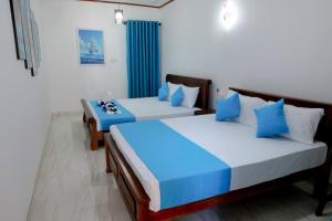 two beds in a room with blue and white at Arunella Beach Villa in Tangalle