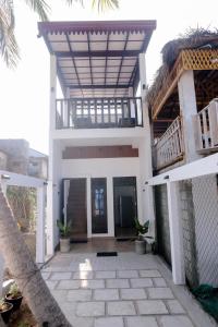 a white house with a balcony and a patio at Arunella Beach Villa in Tangalle
