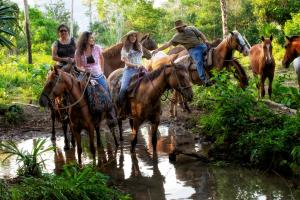 a group of people riding horses through a river at Casa Santa Maria in Benque Viejo del Carmen +26 photos