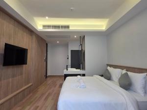 a hotel room with a bed and a flat screen tv at Warm Pillow Hotel Bangkok in Bangkok