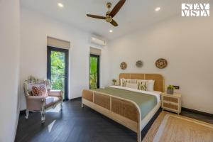 a bedroom with a large bed and a chair at StayVista at Casa Roma - Private Pool in Siolim