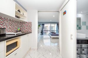 a kitchen with white cabinets and a living room at Hua Hin Condo D - Maysa & Hin Nam in Hua Hin