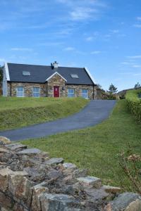 a stone house with a red door and a driveway at 4 Bedroom House By Travel Lets Holiday Homes Downings With Beautiful Ocean View in Downings