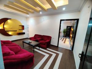 a living room with two red couches and a table at Hotel Grace Inn Multan in Multan