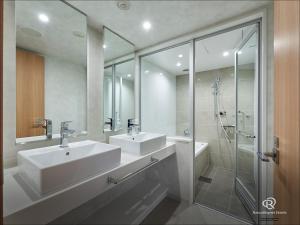 a white bathroom with two sinks and a shower at Daiwa Roynet Hotel Yokohama-Koen in Yokohama