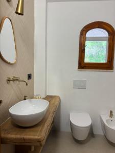 a bathroom with a sink and a toilet and a mirror at Baia Dorata beach apartments in Porto Istana +52 photos