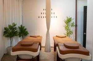 two tables and two stools in a room with plants at NA Hoian Hotel in Hoi An
