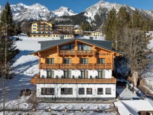 a large wooden building in the snow with mountains at Pension Savisalo in Ramsau am Dachstein