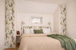 a bedroom with a bed with white walls and a window at Smålandstorpets lanthotell in Hok