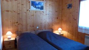 um quarto com paredes de madeira e 2 camas e 2 candeeiros em Chalet le Feufy em Morzine