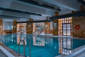 a large swimming pool in a building with windows at The Old Village Hotel & Resort in Wadi Musa