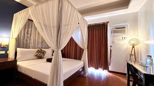 a bedroom with a bed with a canopy at Hotel Palacio Puerto Princesa in Puerto Princesa City +21 photos