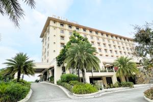 a hotel with palm trees in front of a building at Mella Hotel Manila near NAIA Airport in Manila