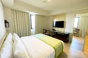 a hotel room with a bed and a desk and a television at Mella Hotel Manila near NAIA Airport in Manila
