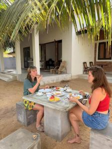 two women sitting at a table eating food at Ma'Moon Beach Villa in Wadduwa