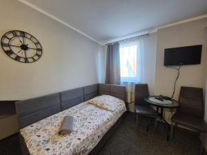 a bedroom with a bed and a clock on the wall at Zajazd pod Lwem in Trzebnica