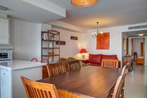 a kitchen and living room with a wooden table and chairs at Sea You Apartamentos Valencia Port Saplaya in Port Saplaya
