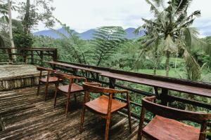 a row of chairs and tables on a deck with mountains at Four Mountains Villa Bedugul by AGATA in Bedugul +21 photos