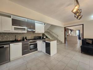 a kitchen with white cabinets and a living room at Mira lune guesthouse in Flic-en-Flac