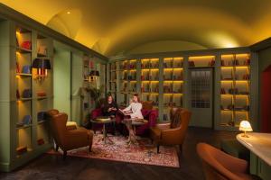 two people sitting in a room with a library at Wonder - The Luxury Boutique Hotel in Budapest