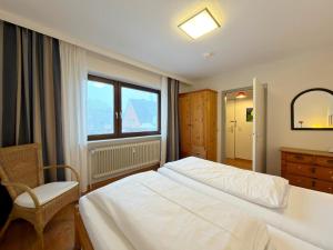 a bedroom with a bed and a chair and a window at Gemütliches App in Westerland mit Hund in Süderende