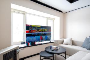 a living room with a white couch and a tv at Biei Sakura Stay in Biei