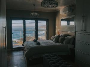 a bedroom with a large bed with a large window at Dolphin View Accomodation in Strandfontein