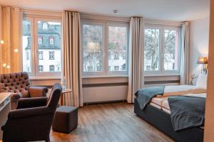 a bedroom with a bed and a chair and windows at Bartmanns Haus & Schwan GmbH in Dillenburg