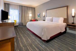 ein Hotelzimmer mit einem großen Bett und einem Flachbildfernseher in der Unterkunft Hampton Inn Commerce in Commerce
