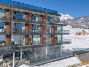 an apartment building with a pool in the snow at Hotel Purvita - Ski In Ski Out - Infinity Pool in Maranza