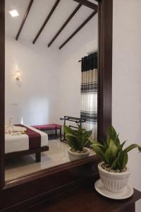 a bedroom with a bed and two plants in a mirror at Villa Sanitha in Ambalangoda +44 photos