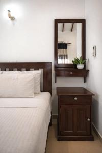 a bedroom with a bed and a dresser with a mirror at Villa Sanitha in Ambalangoda