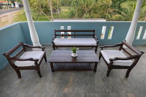 a porch with three chairs and a table and a bed at Villa Sanitha in Ambalangoda