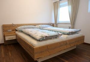 1 dormitorio con cama de madera con almohadas y ventana en Ferienwohnung Köchl, en Münster