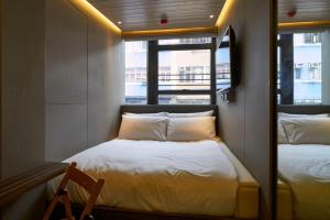a small room with two beds and a window at M Plus Hotel in Hong Kong