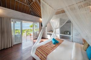 a bedroom with a white bed with a canopy at Bukit Taman Cottages in Nusa Lembongan