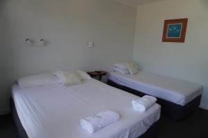 two beds in a room with white sheets and towels at Ocean View Motel Bowen in Bowen +22 photos