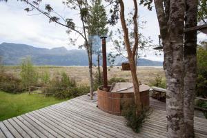 a hot tub on a wooden deck next to a tree at Mareas Ralun Lodge in Ralún