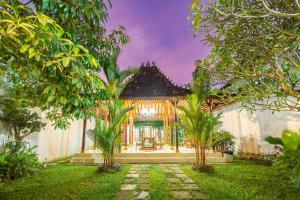 a house with a garden with trees in front of it at Villa Omah Rindu in Yogyakarta