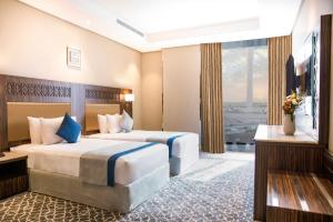 a hotel room with two beds and a large window at SwissBlue Hotel Jeddah in Jeddah