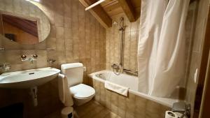 a bathroom with a toilet and a tub and a sink at Hotel du Cheval Blanc in Nods
