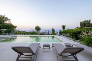 a swimming pool with two chairs and a table and a pool at Vista by Del Sol Villa in Rhodes Town