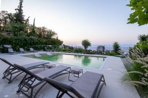 a swimming pool with chairs and a table at Vista by Del Sol Villa in Rhodes Town