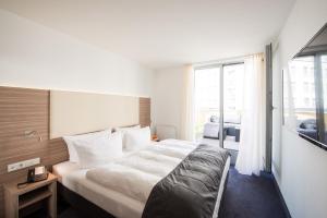 ein Schlafzimmer mit einem großen Bett und einem großen Fenster in der Unterkunft Book Hotel Leipzig in Leipzig