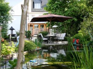 um pátio com uma mesa e um guarda-chuva sobre um lago em Hotel "Schloss Friedestrom" em Dormagen