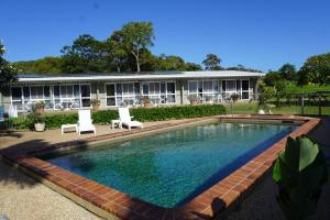 a swimming pool with two chairs and a building at Ocean View Motel Bowen in Bowen