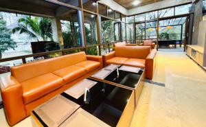 a living room with orange leather furniture and large windows at Privee Dhaka - PRIVEE RESORT & RESTAURANT in Bholānāthpur
