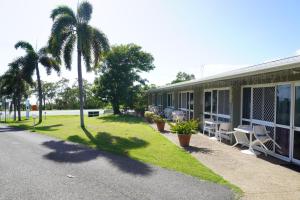 a building with palm trees and chairs next to it at Ocean View Motel Bowen in Bowen