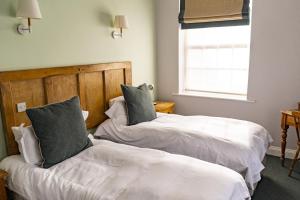 two beds in a room with white sheets and pillows at The Old Cannon Brewery in Bury Saint Edmunds