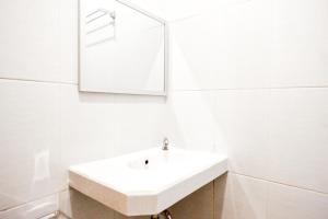 a white bathroom with a sink and a mirror at RedDoorz @ Jalan Wonosari KM.9 in Yogyakarta